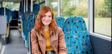 Eine Frau sitzt in einem Bus und schaut uns an